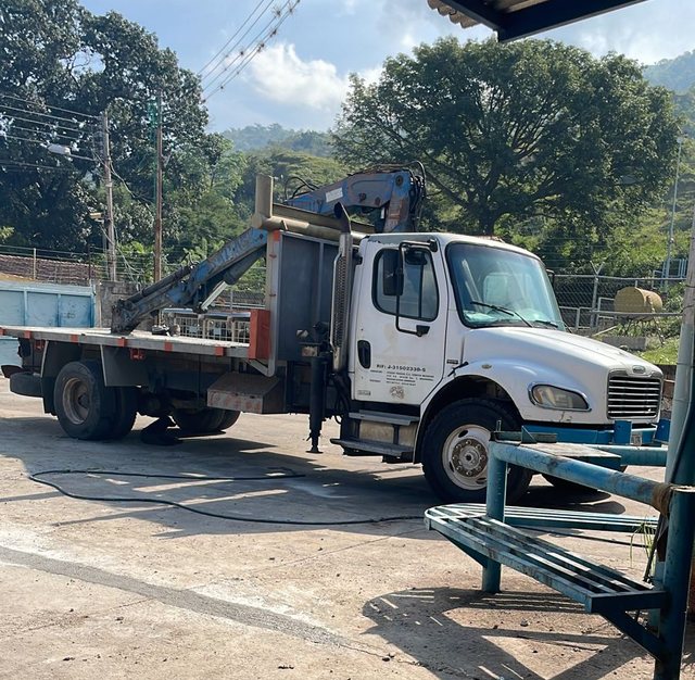 Camión grúa Freightliner con brazo hidráulico en el patio