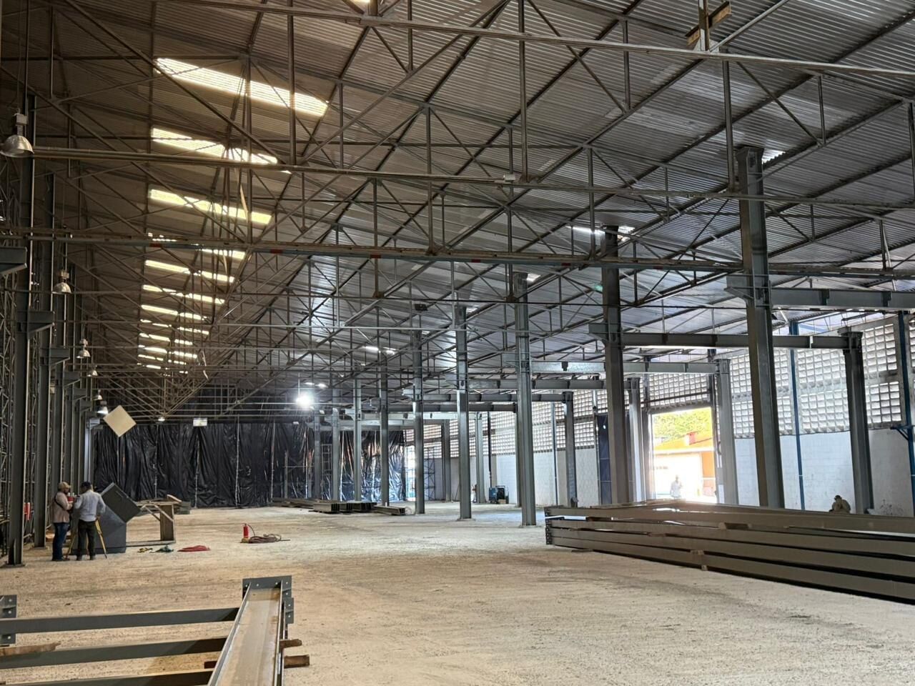 Interior de un galpón con columnas y cerchas metálicas y perfiles listos para montaje